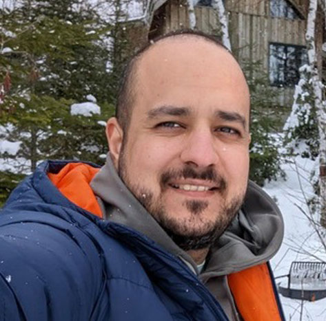 Saman Azizkhani standing outside with snow and trees in the background