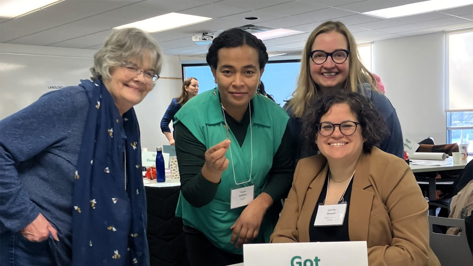 Four women smiling together in office room