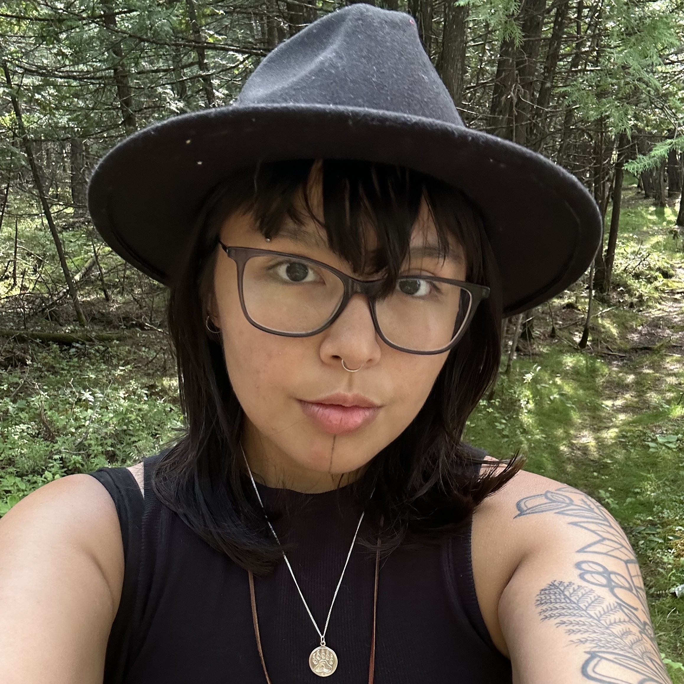 Ryleigh Todd-Moore wearing a hat and glasses in front of trees